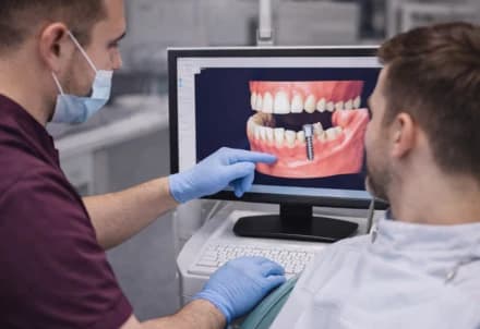 Odontoiatra che mostra a un paziente la posizione dell'impianto sulla simulazione a schermo